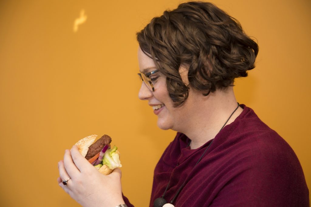 A consumer smiling at a hamburger. 
